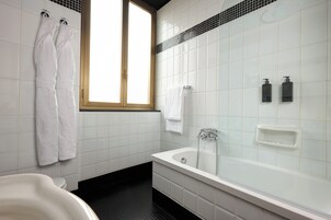 A modern bathroom with a bathtub, a window, and white tiles.