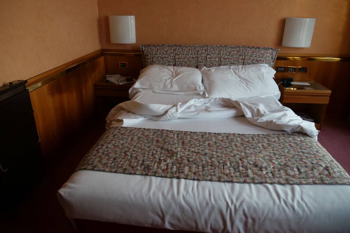Una habitación de hotel con una cama, dos mesitas de noche y un buró.