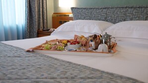 Une chambre d’hôtel avec un lit soigneusement fait, un plateau de petit-déjeuner, une table de chevet avec une lampe et une petite table de nuit avec un téléphone et un livre.