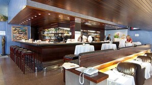 Un espace bar doté d’un long comptoir, de plusieurs options de sièges, notamment des banquettes et des tables hautes, et d’un bar bien approvisionné en bouteilles de toutes sortes.