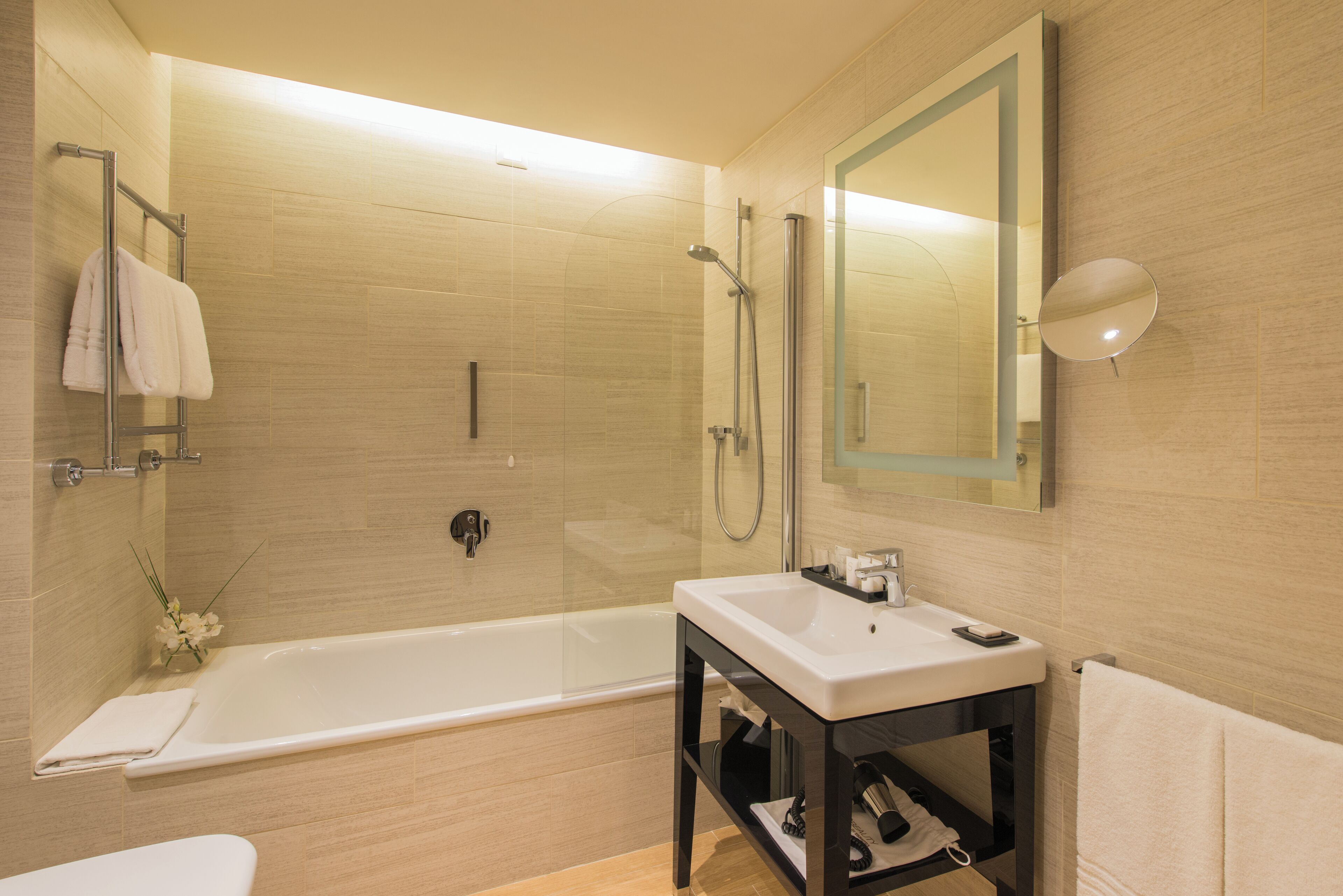 A modern bathroom with a bathtub, a sink, and a shower area.