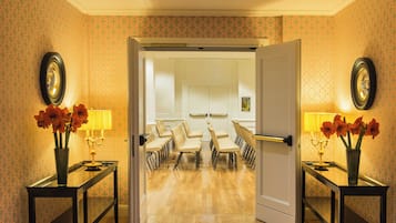 Un'area di accoglienza hotel con una sala conferenze, una reception e un salottino con vasi di fiori.