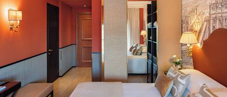 A hotel room with a bed, bedside table, lamp, and a view of a cityscape through a window.