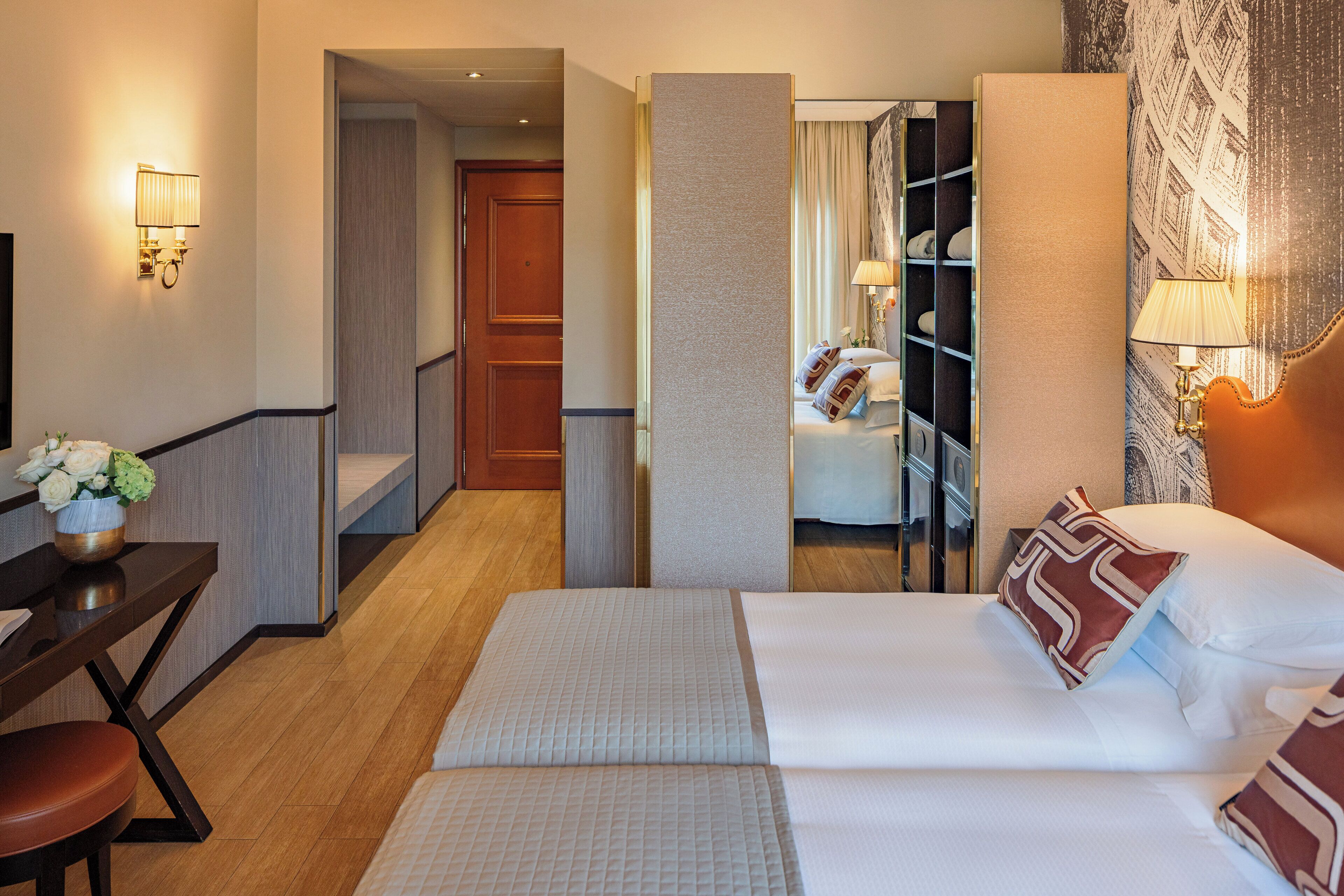 A hotel room with a bed, a desk, a chair, and a nightstand.