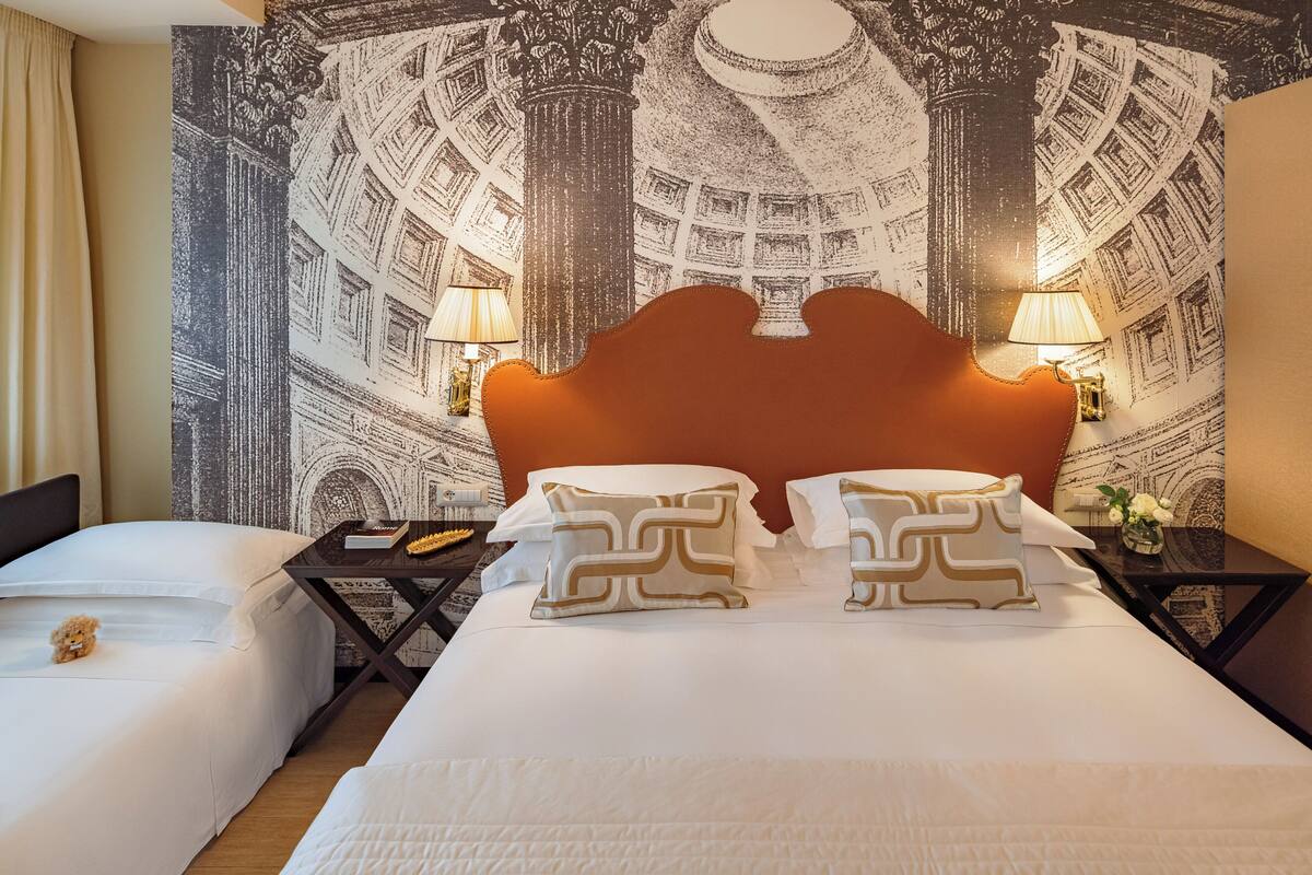 A hotel room with a large bed, two bedside tables, and a decorative tapestry on the wall.