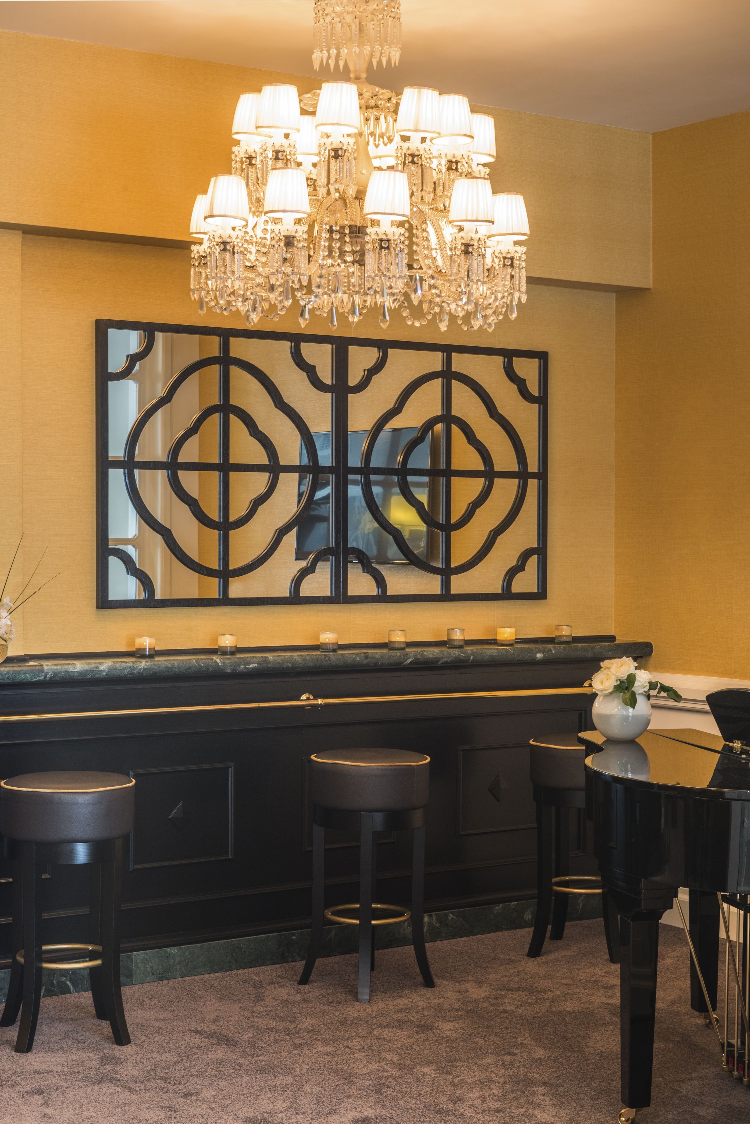 A bar area with a chandelier, a decorative wall piece, and a piano.
