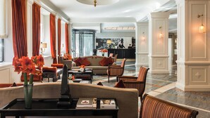 A spacious lobby with a sofa, chairs, a coffee table, and a vase of flowers.