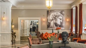 A spacious lobby with a marble floor, a large painting, and a statue on a coffee table. - Starhotels Michelangelo (Rome)