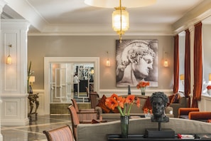 A spacious lobby with a marble floor, a large painting, and a statue on a coffee table. - Starhotels Michelangelo (Rome)