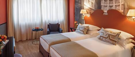 A hotel room with two beds, a desk, a chair, a small table, and a large window with curtains.