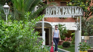 A hotel entrance with a sign reading "HOTEL PANAMA," surrounded by lush greenery and potted plants. - Hotel Panama Garden (Rome)