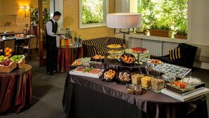 A buffet setup with various food items, a waiter, and a lounge area with a sofa and lamp. - Hotel Panama Garden (Rome)