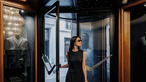 A woman in a black dress standing at a revolving door with a mannequin in a suit on the left. - Valadier Hotel (Rome)