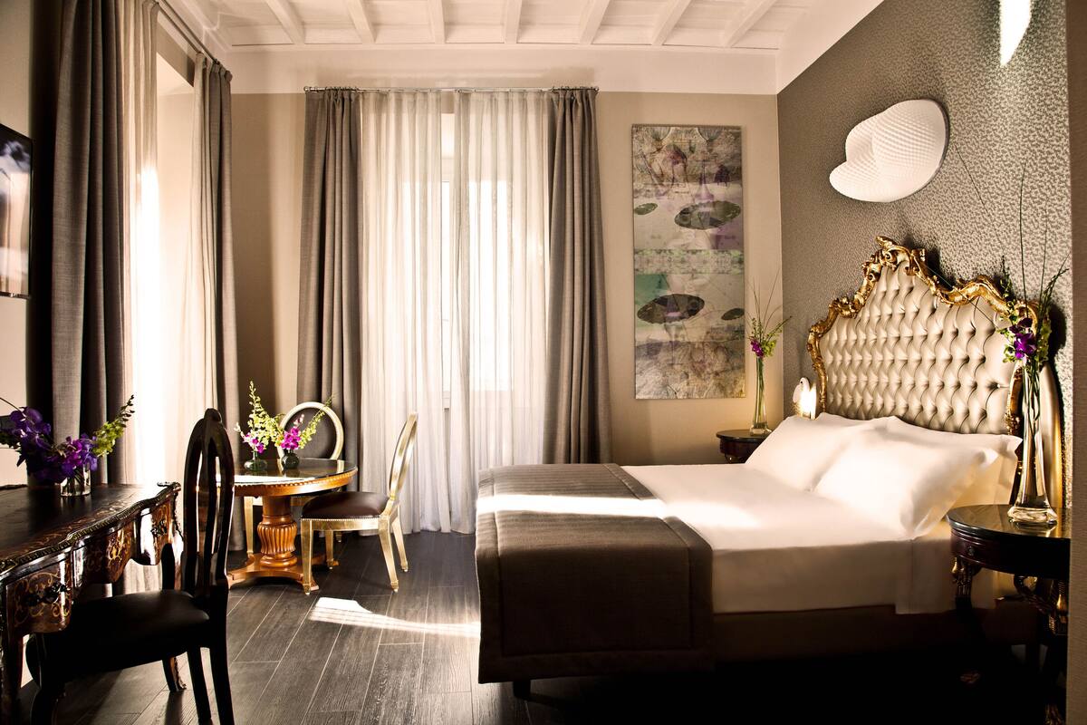 Une chambre d’hôtel avec un grand lit, un bureau avec une chaise, une table ronde et un miroir décoratif.