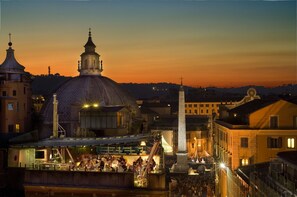 A historic building with a large dome and a bell tower, surrounded by other structures and a crowd of people. - Valadier Hotel (Rome)