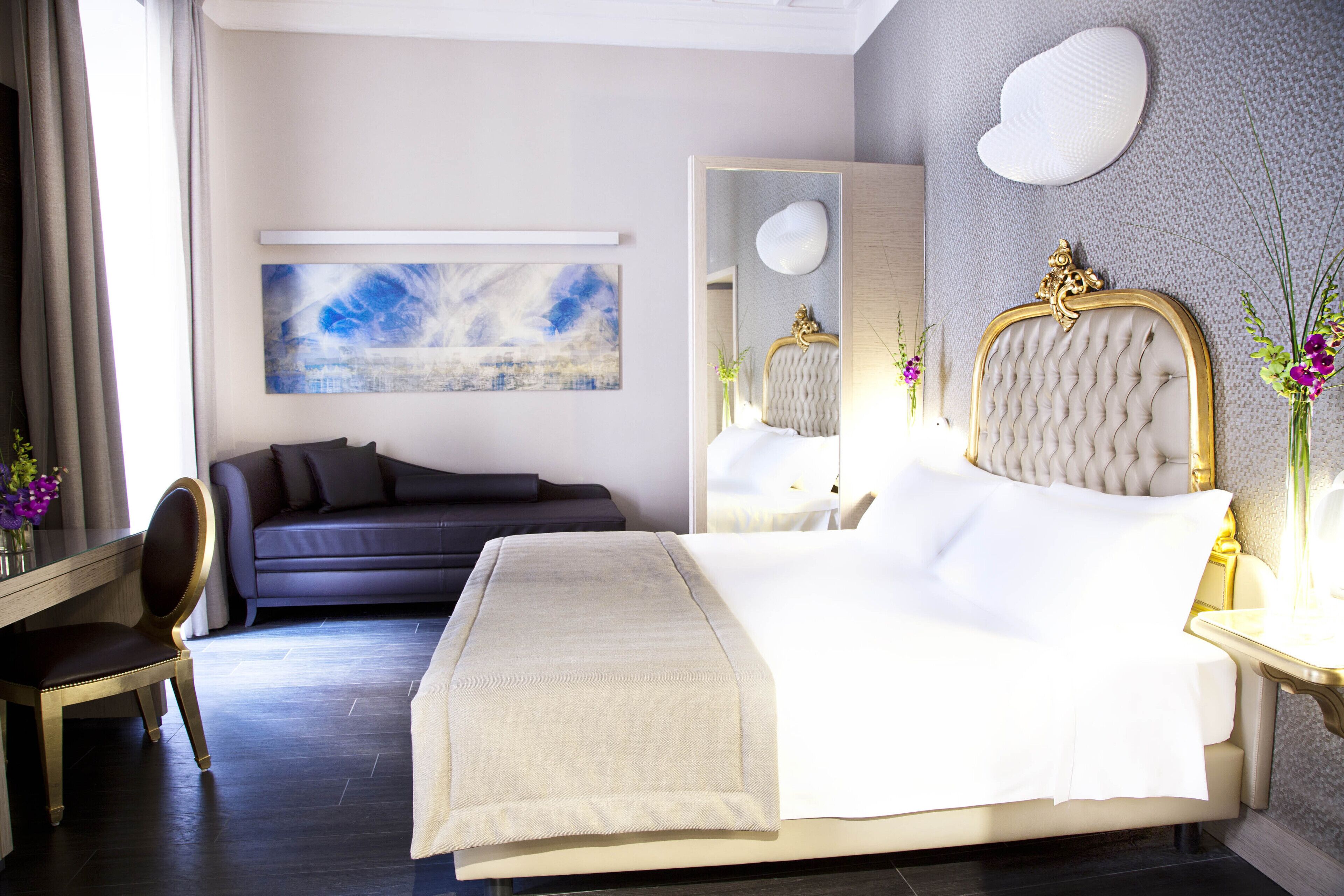 Une chambre d’hôtel moderne avec un grand lit, un canapé, un bureau et un miroir.