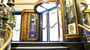 Une entrée imposante avec un escalier en marbre, une porte tournante et une balustrade en verre.