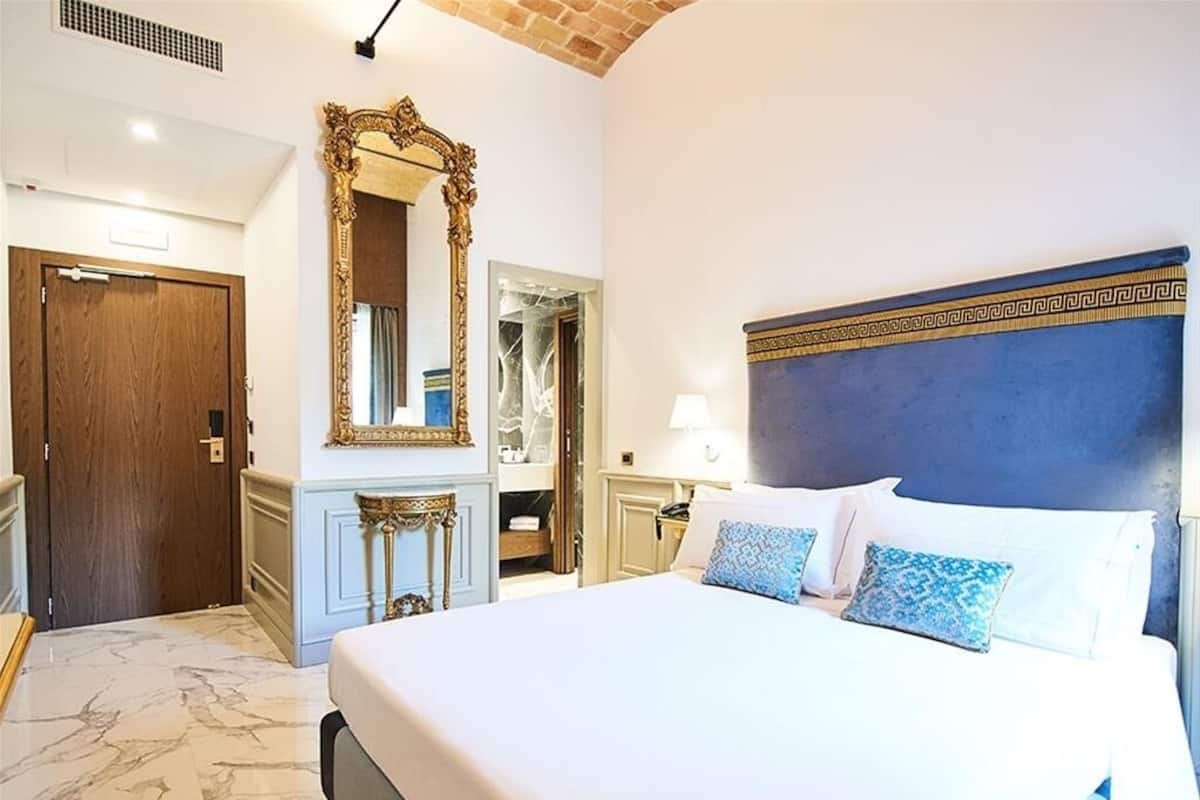 Une chambre d’hôtel avec un grand lit, un miroir, une armoire et une porte.