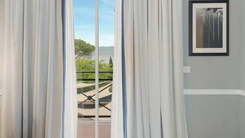Une pièce avec vue sur un balcon, un tableau encadré au mur et une fenêtre avec des rideaux.
