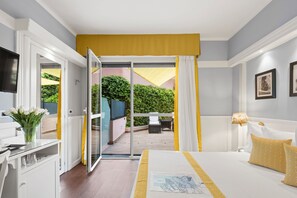 Ein Schlafzimmer mit Bett, Schreibtisch und Stuhl. Ein Balkon bietet Blick auf Grünflächen.