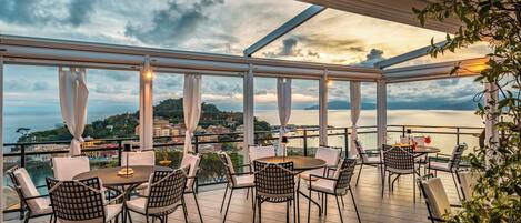 Una terraza con mesa y sillas, con vistas a un paisaje pintoresco de una masa de agua y tierra distante.