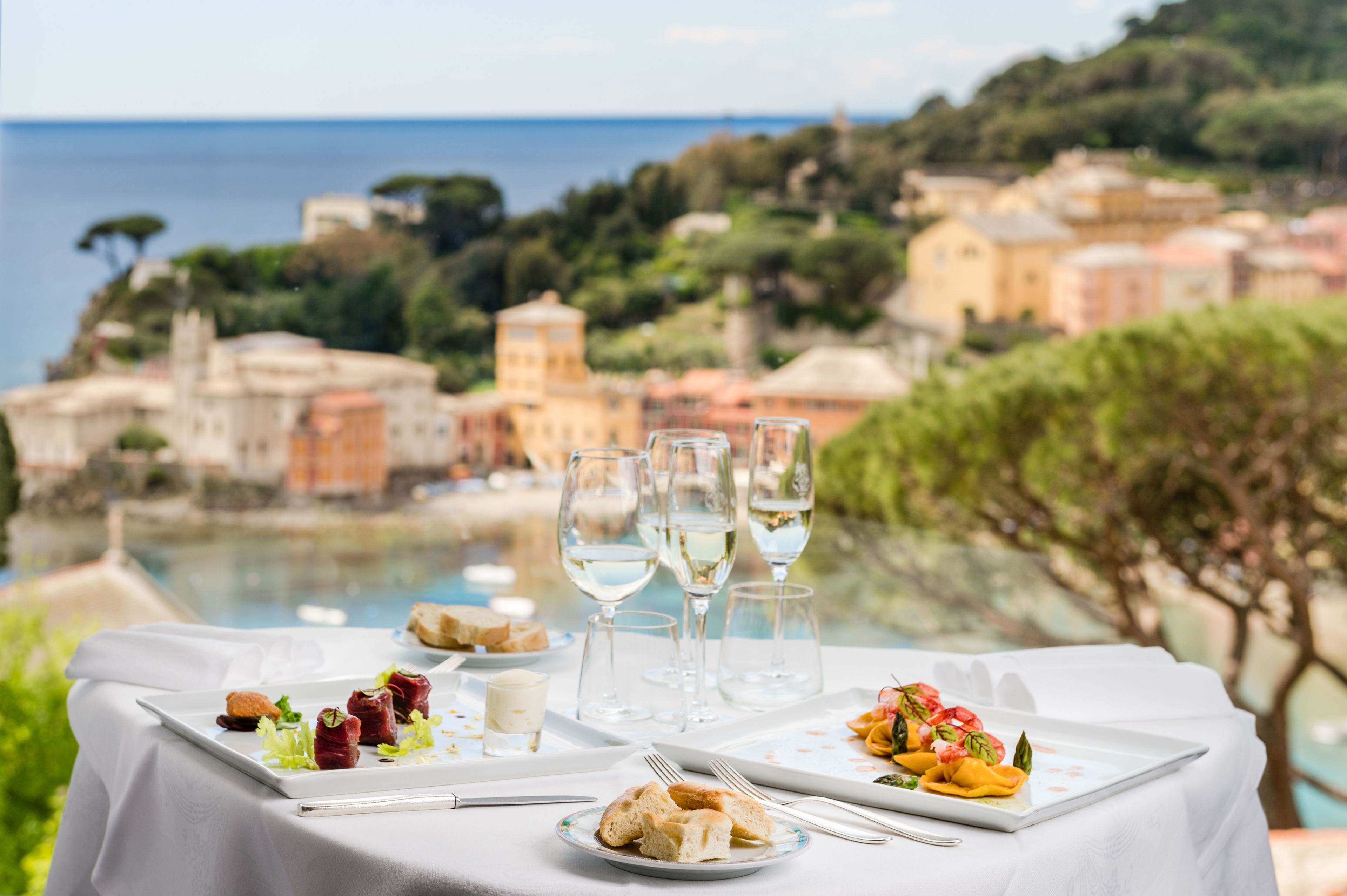 A table set for a meal with a scenic view of a coastal town and the sea.