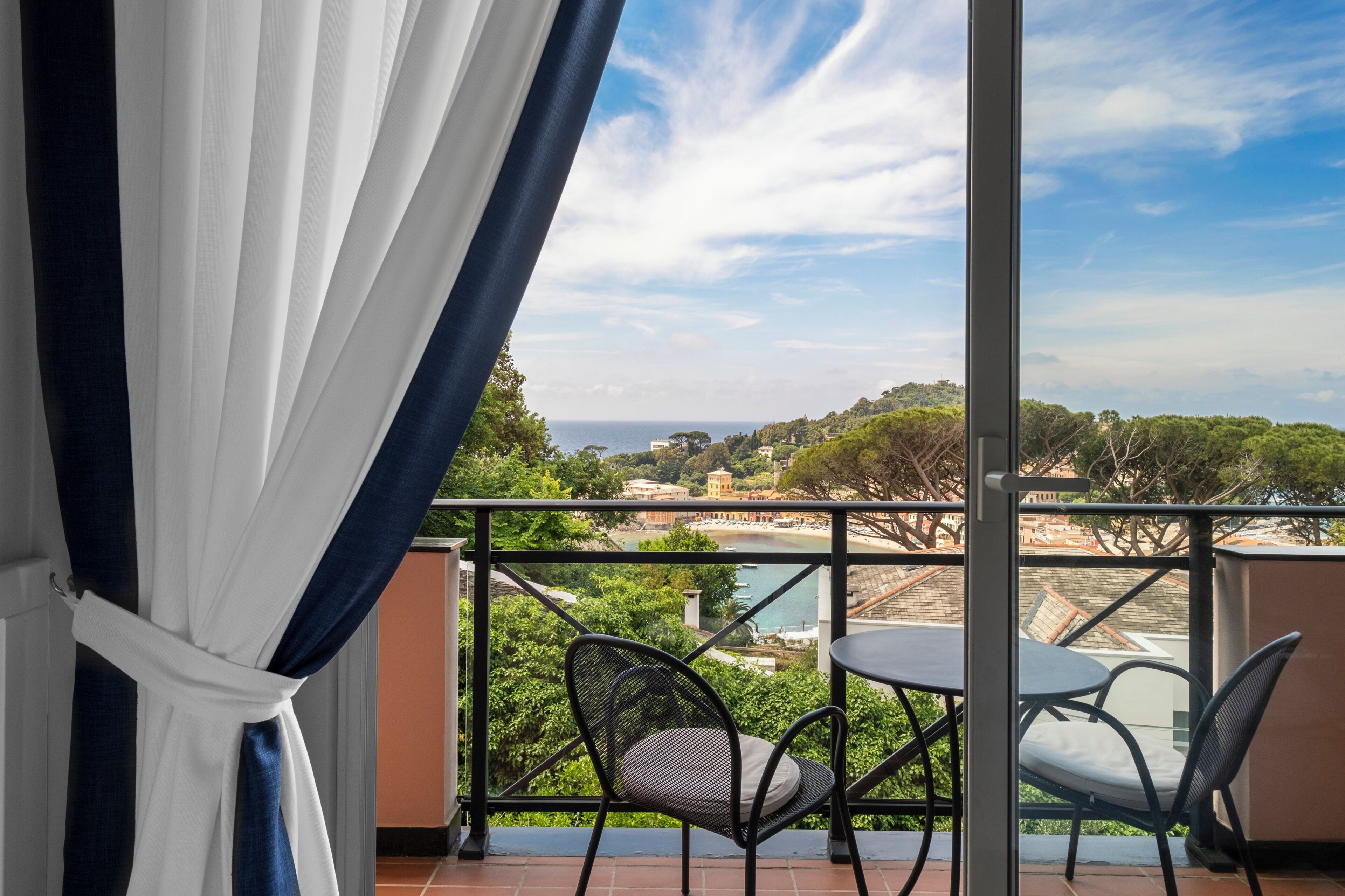 Un balcón con vistas a un paisaje costero, que incluye árboles y edificios.