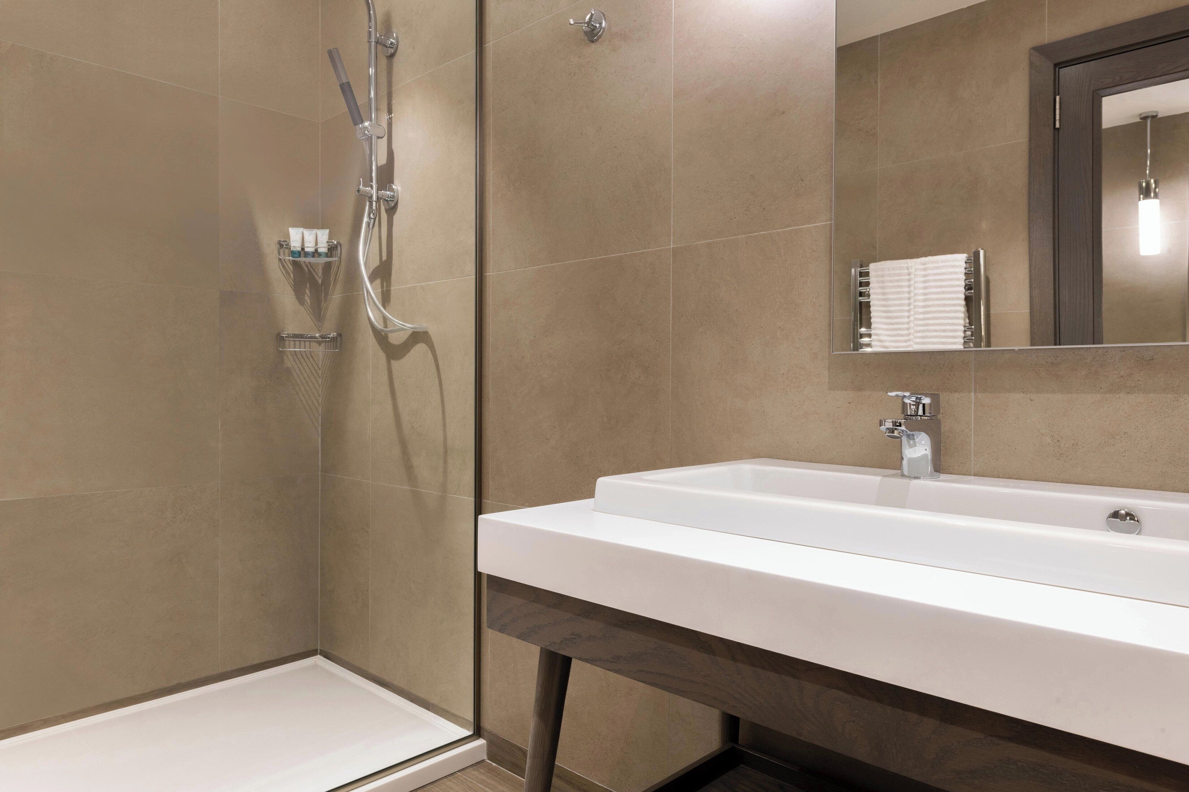 Un baño moderno con ducha, lavamanos y espejo.