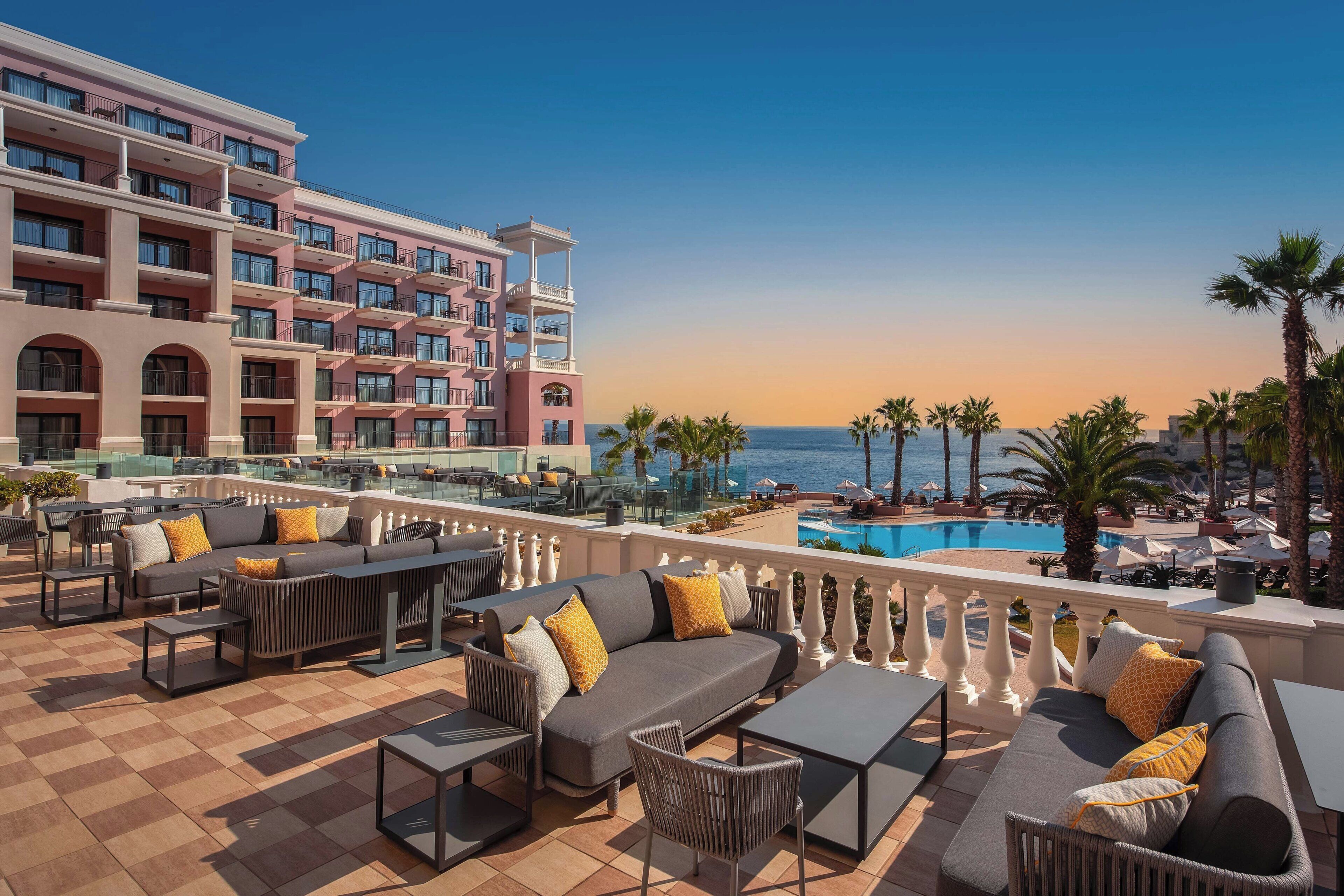 A rooftop lounge with outdoor seating, a pool, and a view of the ocean.
