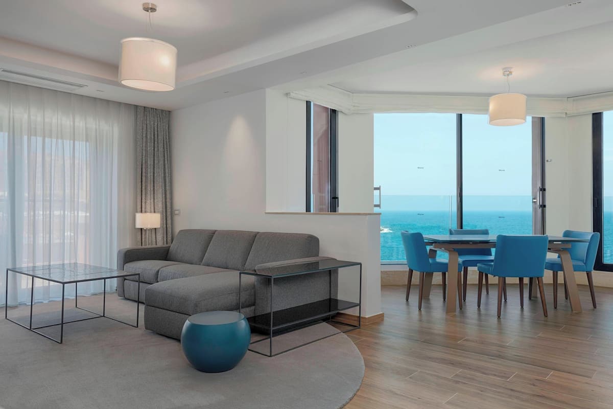 A modern living room with a sofa, coffee table, and dining area with chairs.