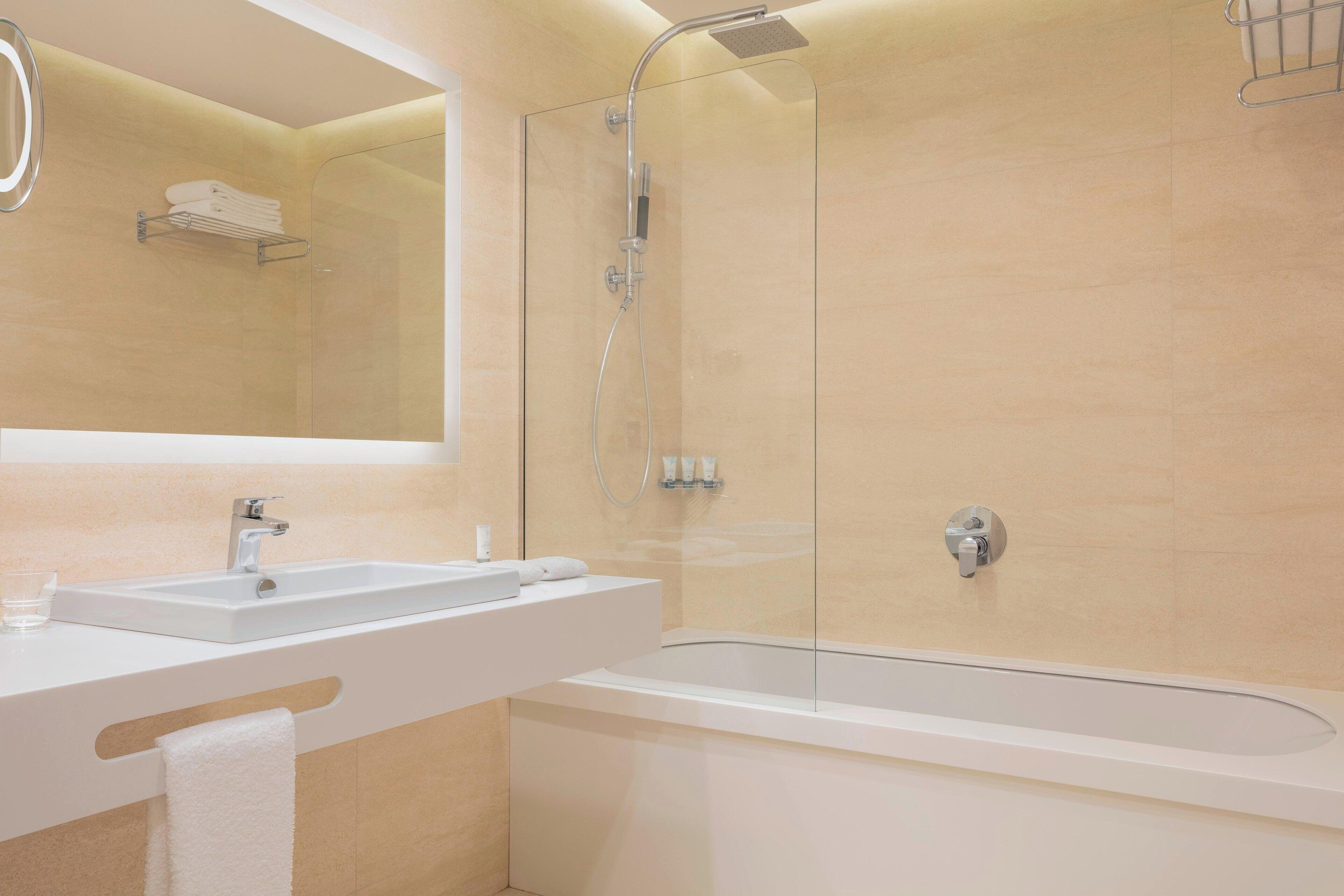 Un baño moderno con ducha de vidrio, lavabo blanco y bañera amplia.