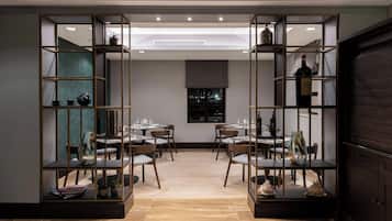 Un comedor de diseño moderno, con una mesa central rodeada de sillas y estanterías decoradas con objetos ornamentales.