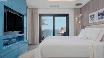 A modern hotel room with a large bed, a flat-screen TV, and a balcony with a view.