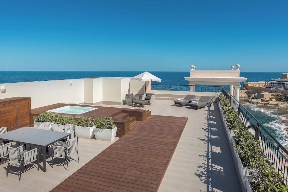 A rooftop terrace with a pool, seating area, and ocean view.