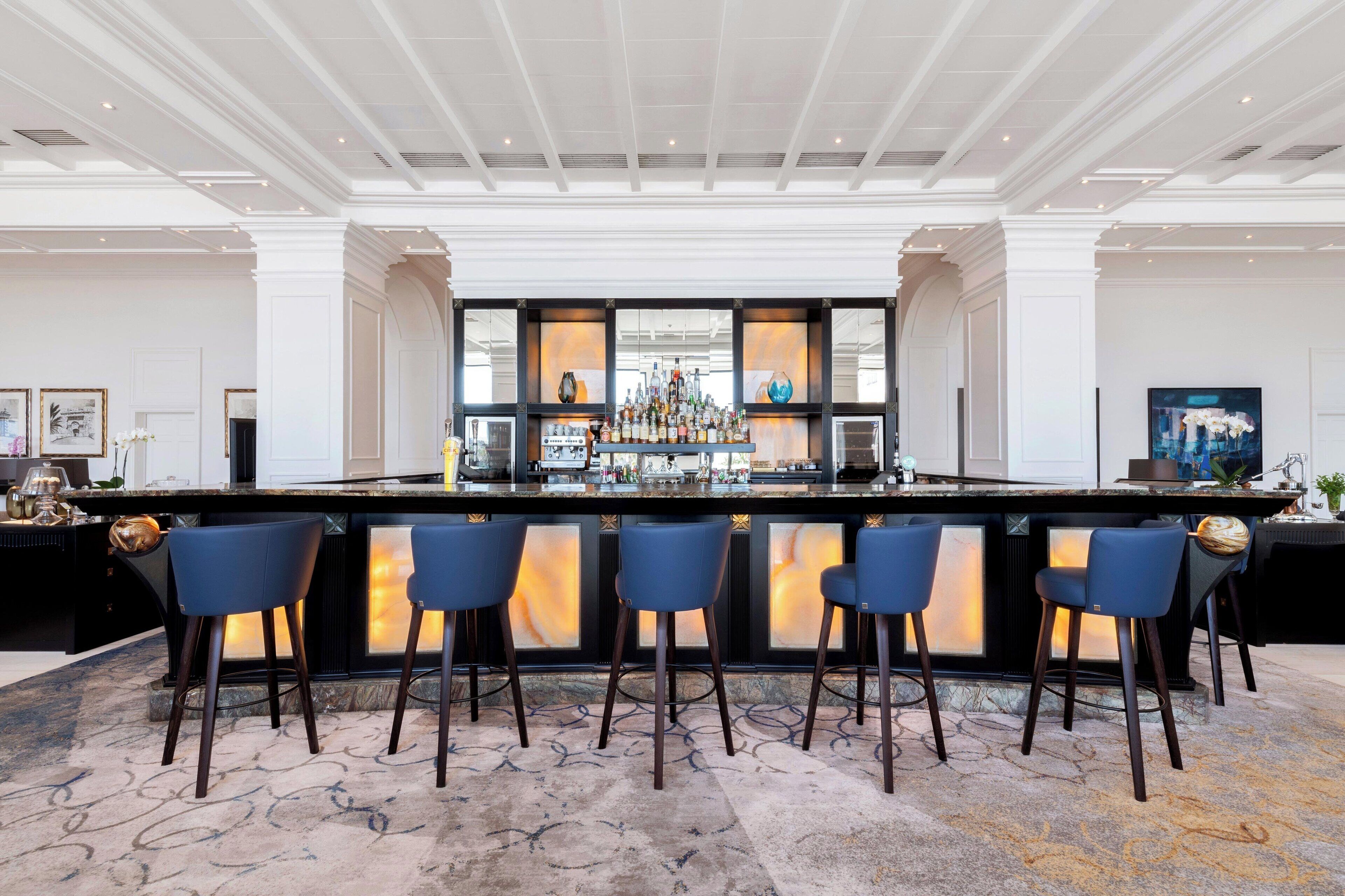 A bar area with a central counter, multiple stools, and a patterned carpet.