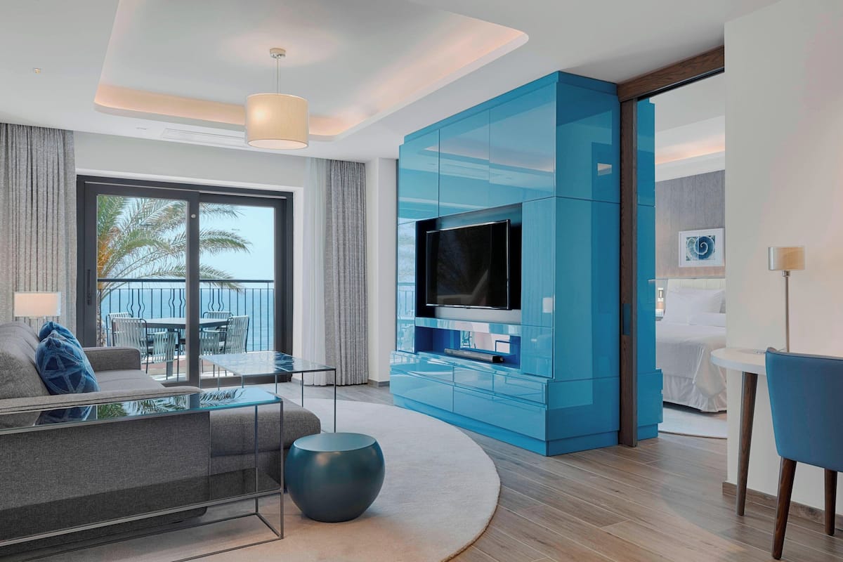 A modern living room with a large flat-screen TV, a glass coffee table, and a blue entertainment unit.
