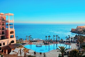 Alberca techada, alberca al aire libre y sombrillas en la alberca