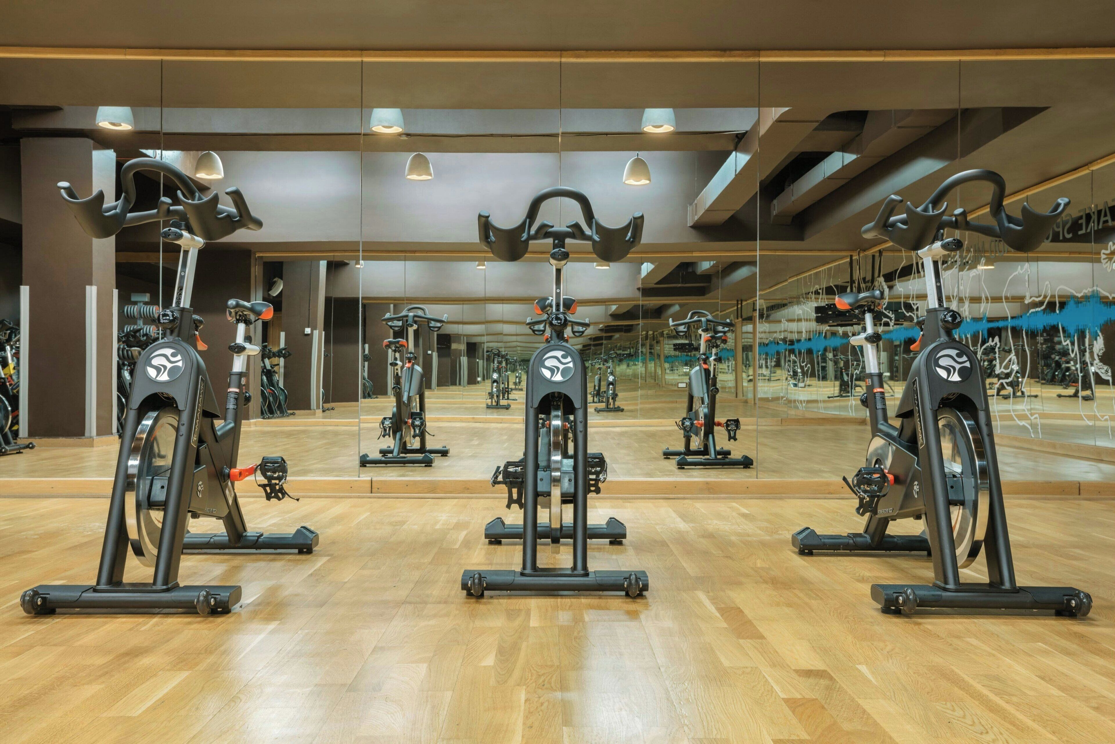 A gym with multiple exercise bikes and mirrors on the walls.