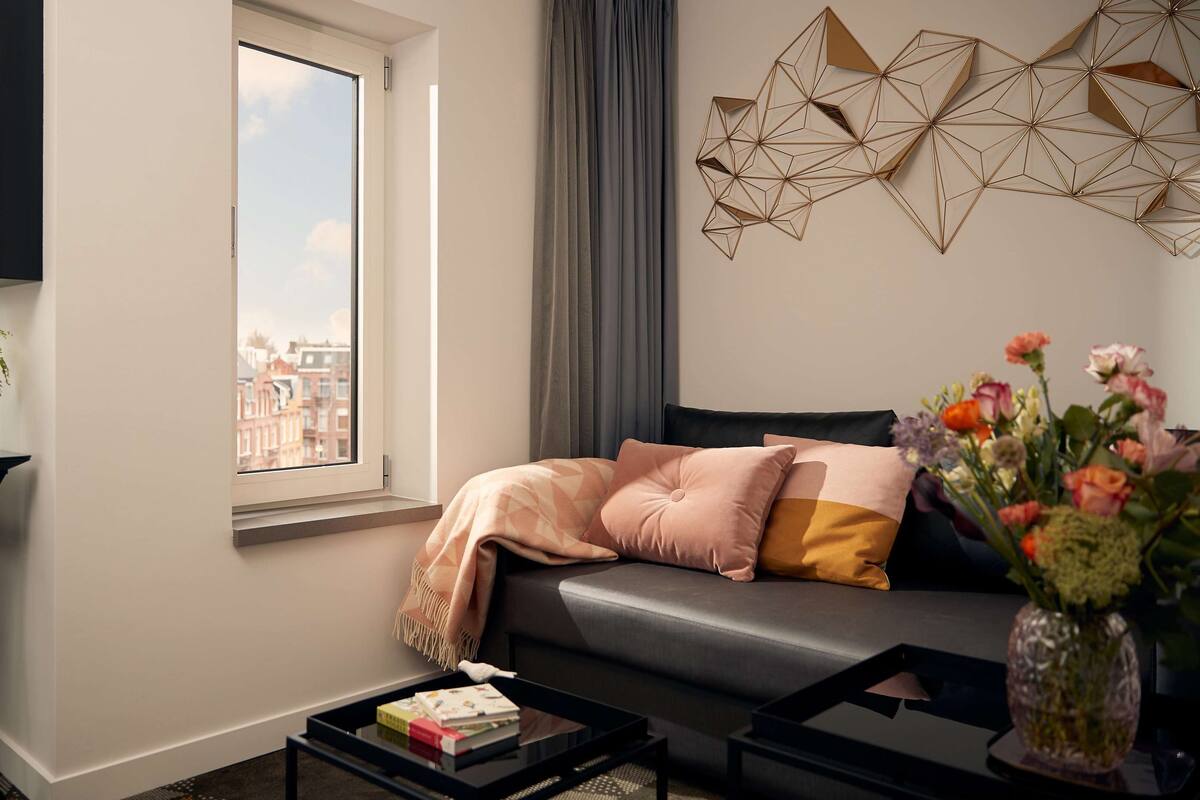 Una sala de estar moderna con un sofá, una mesa de centro, un televisor y un ventanal con vista a la ciudad.