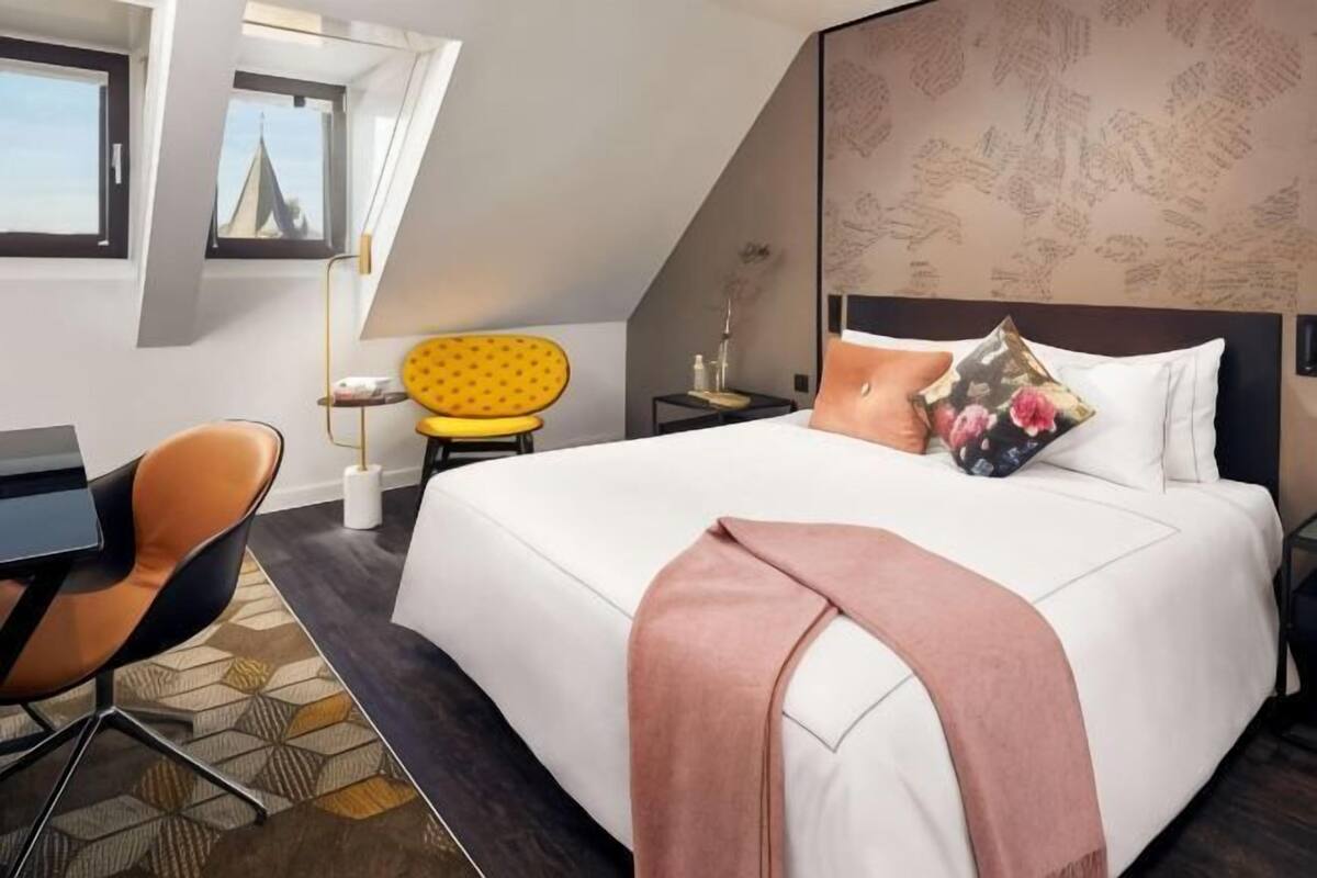 Habitación de hotel moderna con una cama grande, un escritorio, una silla y vistas a la ciudad.