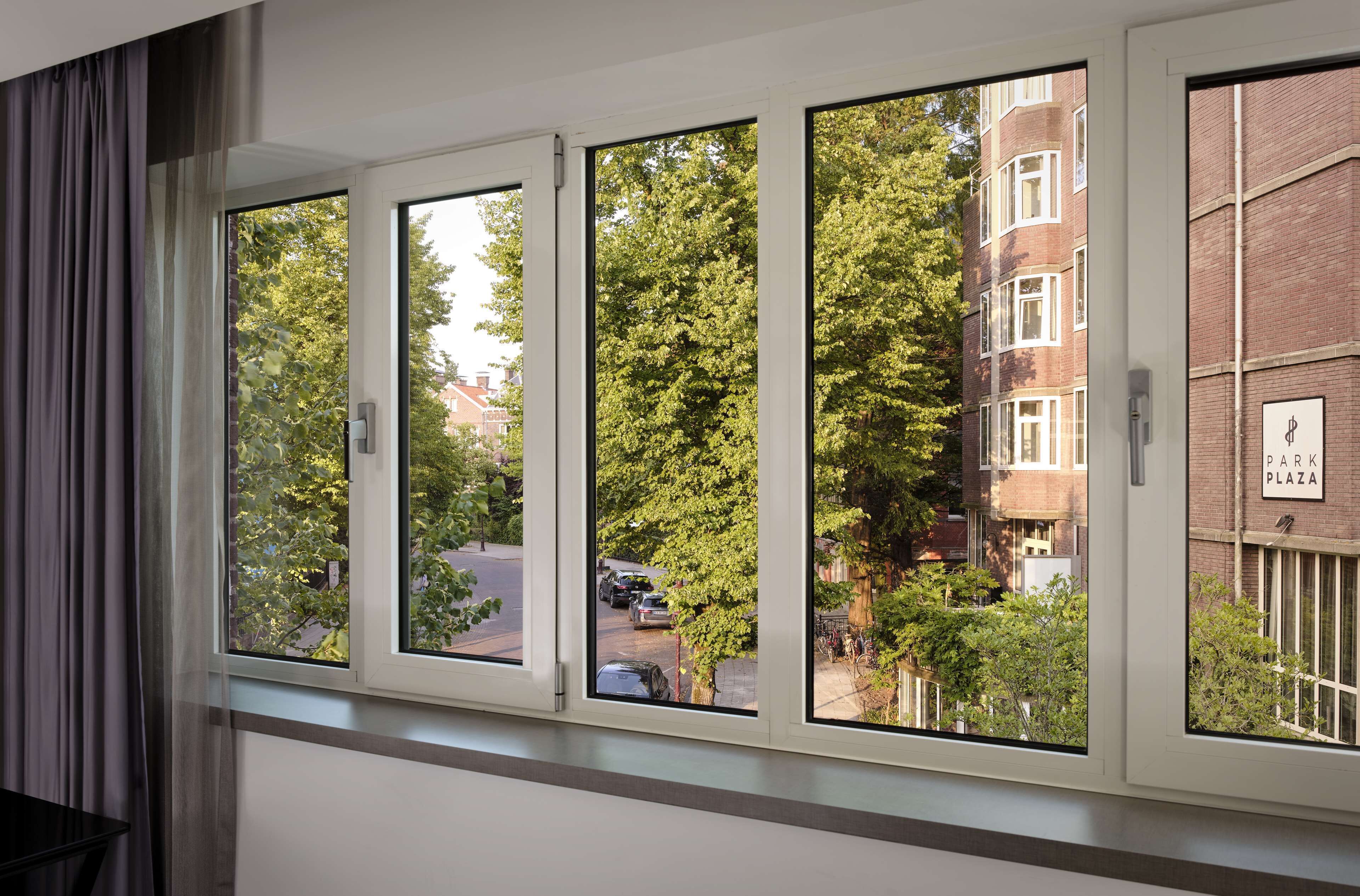 Una ventana con vistas a una calle, un edificio con un cartel que dice "Park Plaza" y un árbol en primer plano.