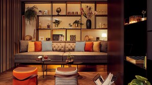 A modern living room with a sofa, ottomans, and a coffee table. There are shelves with decorative items and a globe.