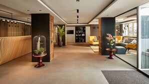 A modern lobby with a reception desk, seating area, and a large window.