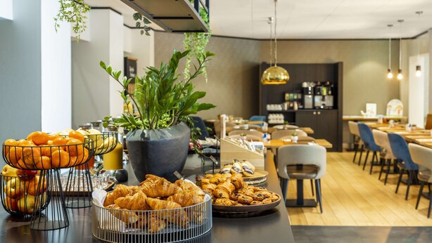 Ein Frühstücksbuffet mit Früchten, Gebäck und einer Topfpflanze.