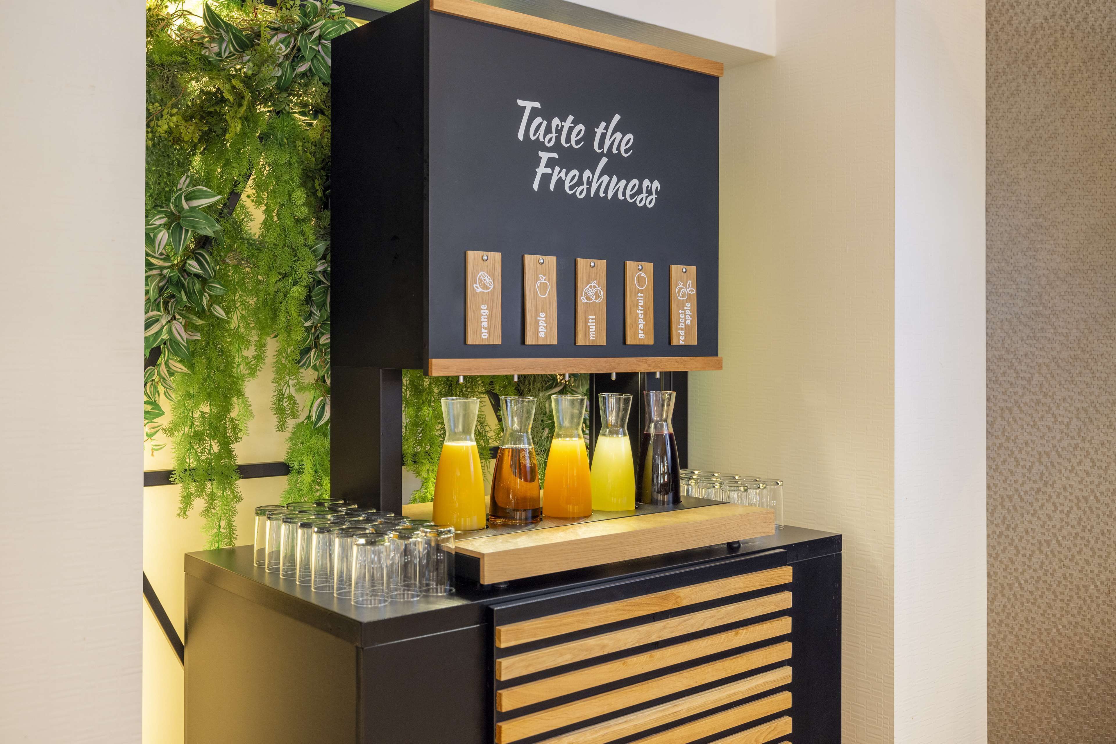 A juice bar with a sign reading "Taste the Freshness" and labels for orange, apple, mint, grapefruit, and red apple juices.