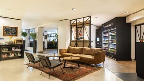 Eine moderne Lounge-Ecke mit einer Ledersofa, zwei Sesseln, einem kleinen Couchtisch und einem Bücherregal.