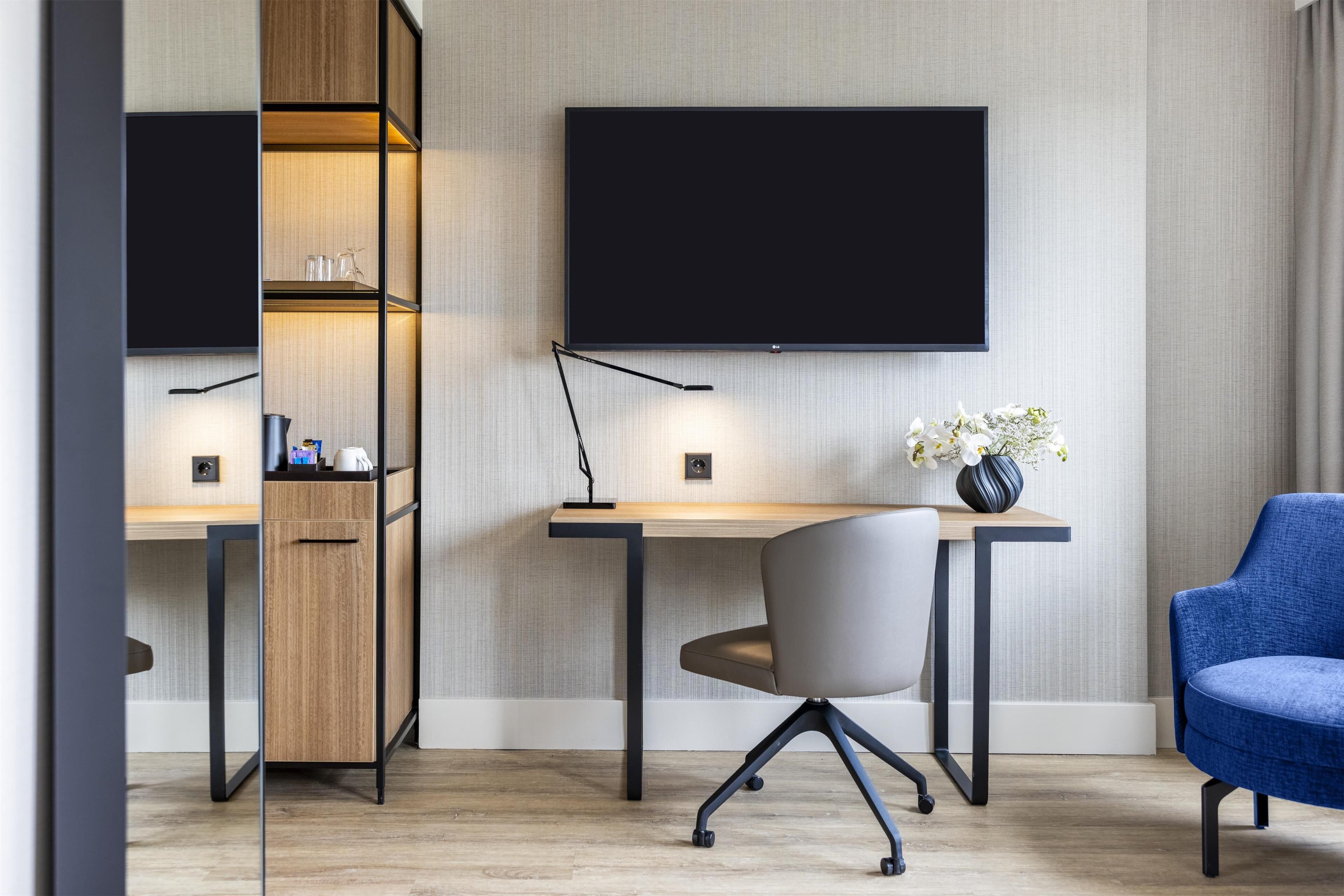 A modern office space with a desk, chair, and a blue armchair.