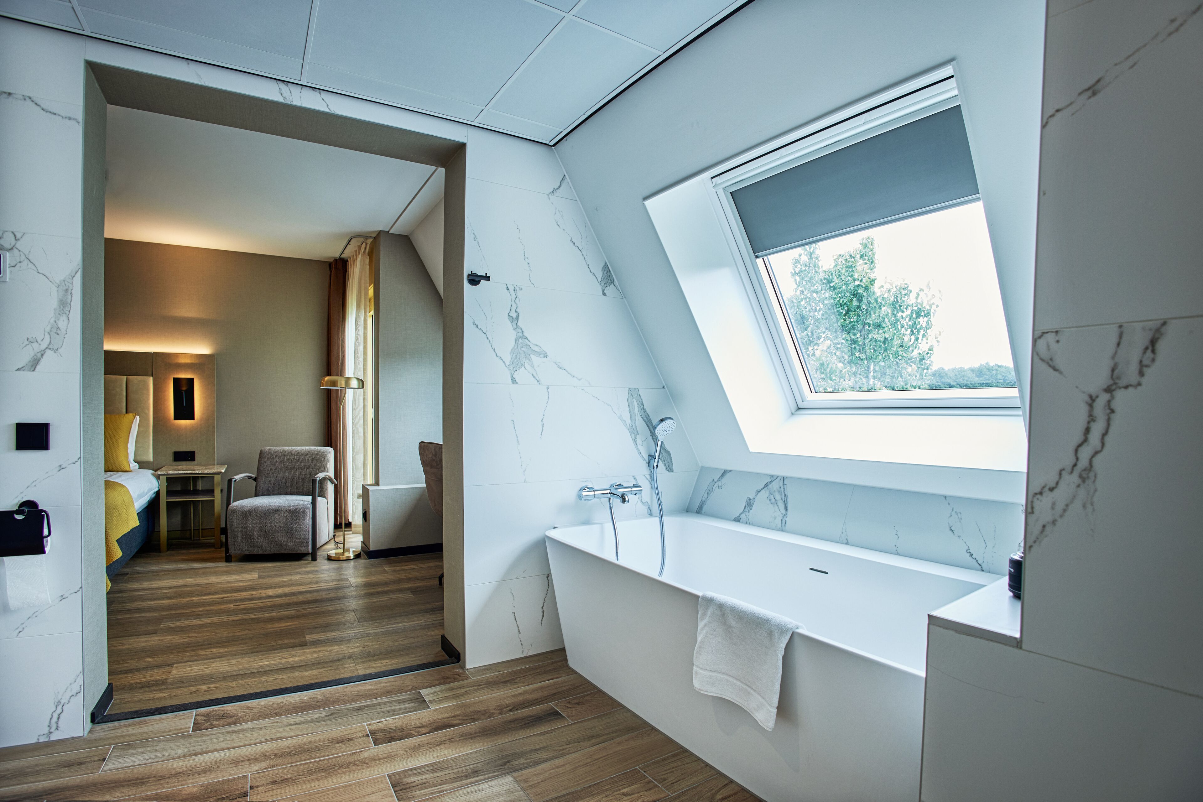 Un baño moderno con una bañera independiente, un ventanal con vistas y suelo de madera.
