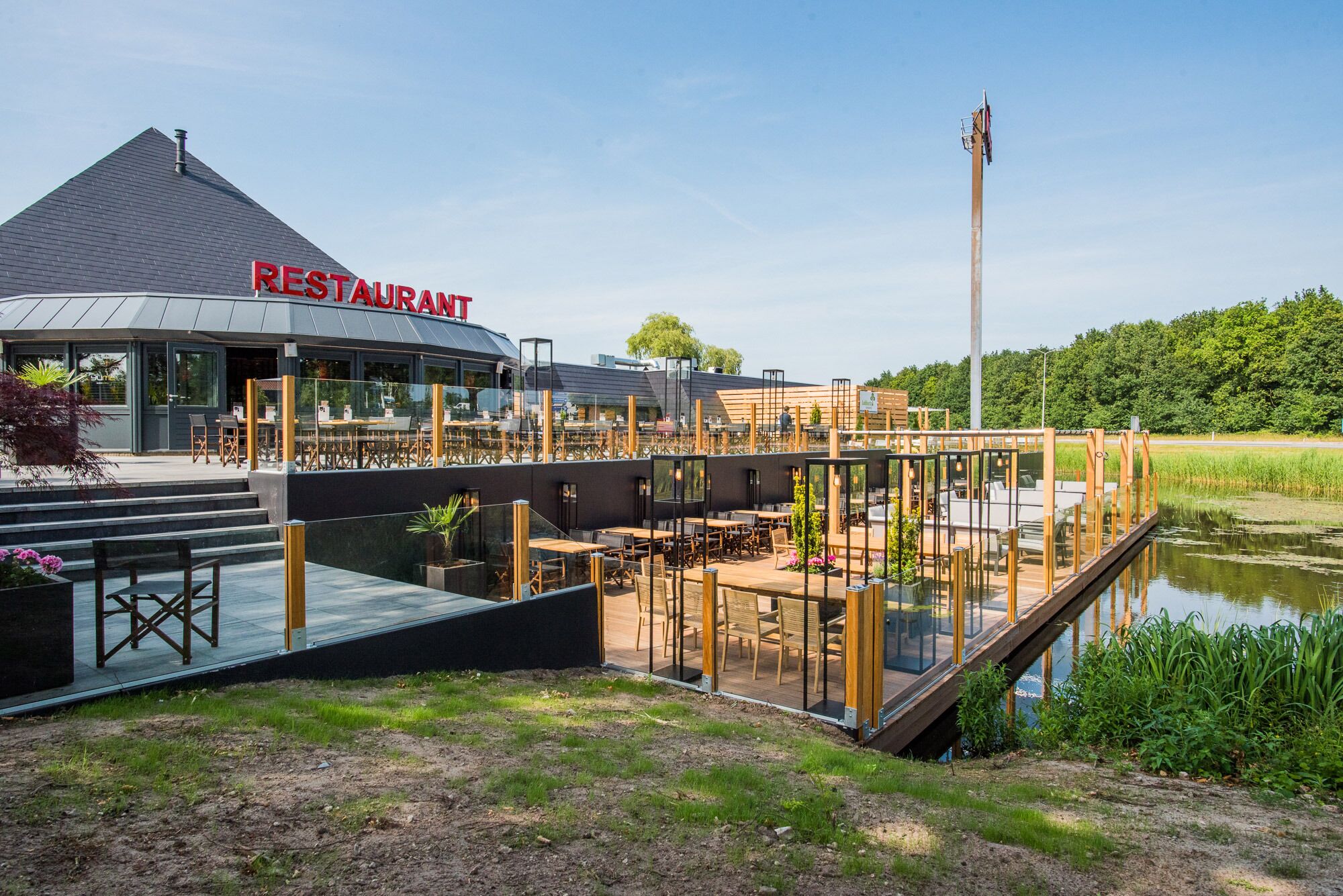Restaurante com design moderno, com área de estar coberta ao ar livre e vista para a água.