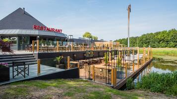 Restaurante com design moderno, com área de estar coberta ao ar livre e vista para a água.
